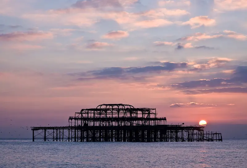 The skeleton of Brighton’s West Pier at dusk under a pink sky
